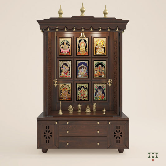 A solid wood mandir with pure brass bells, Tanjore art prints, cutwork designs and storage, tinted in a tamarind brown color
