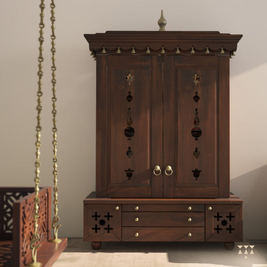 A solid wood mandir with doors, pure brass bells, accessories, cutwork designs and storage, tinted in a tamarind brown color
