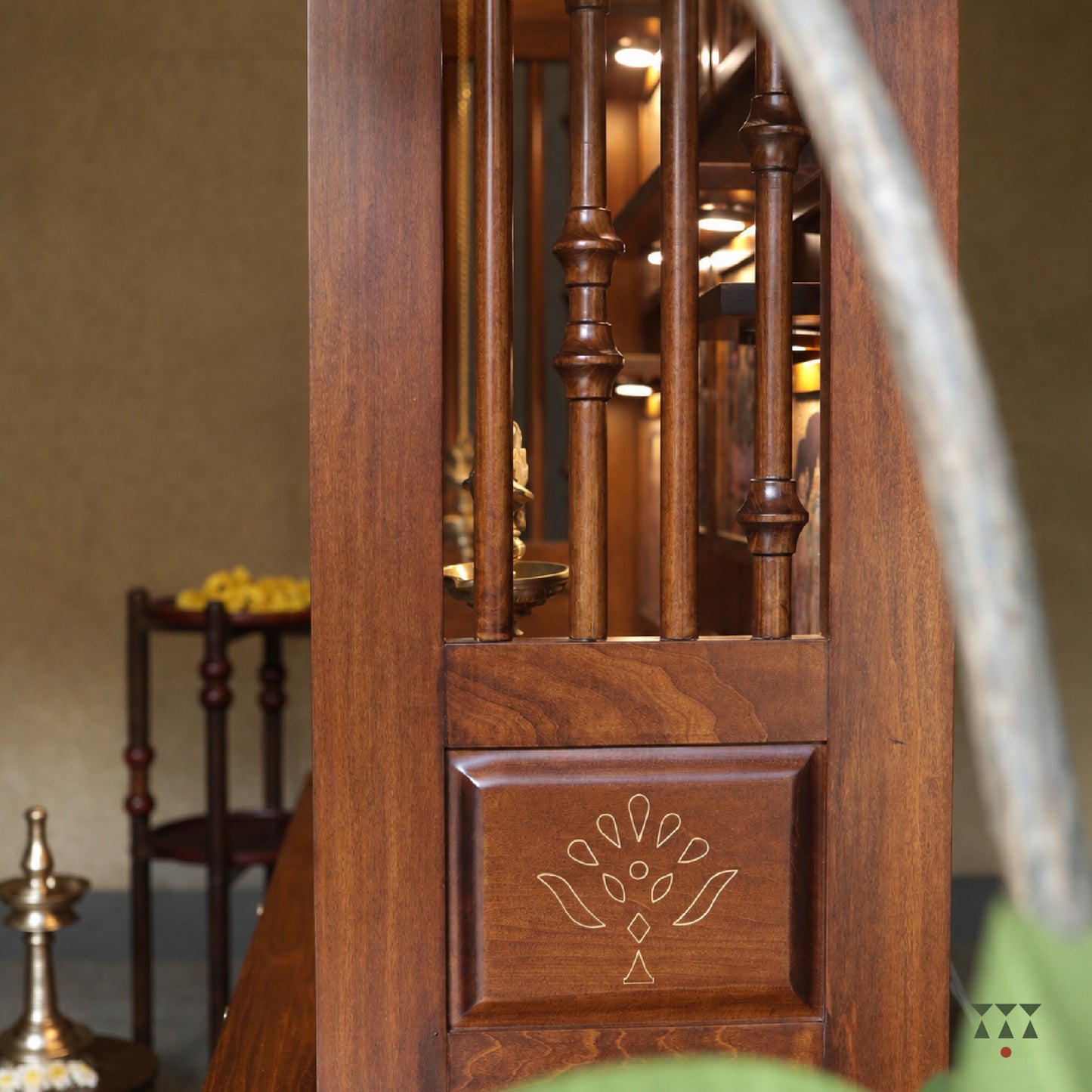 Close-up of a wooden pooja cabinet with intricate carvings and a blurred background