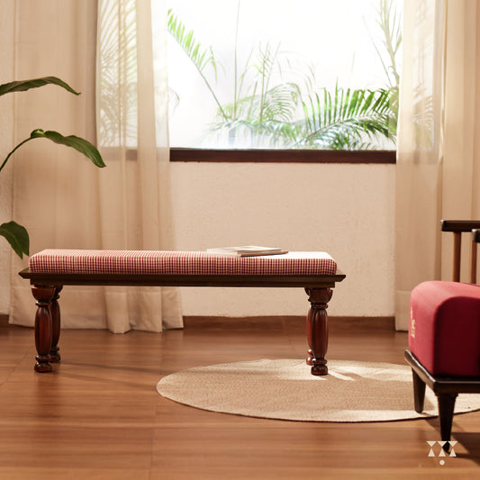 A handcrafted wooden bench with turned legs and a cushioned seat, upholstered in a luxurious checked silk  