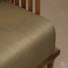 A close up of the colorful, rich silk upholstery of a solid wood statement armchair