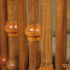 A close up of multiple turned spindles that make the armrest of a solid wood statement armchair