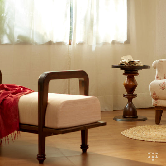 Lifestyle image of a sculpted long wooden bench upholstered in beige silk, tinted in Mocha Brown with a Beet Red accent