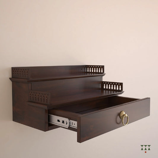 A compact wooden, wall mounted Mandir with steps, cutwork, storage and pure brass elements tinted in tamarind brown