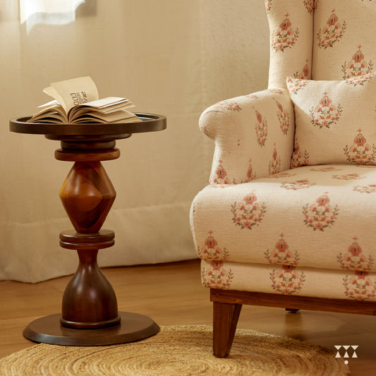 A solid wood wing chair draped in a floral printed white fabric with a matching cushion, tinted in mocha brown