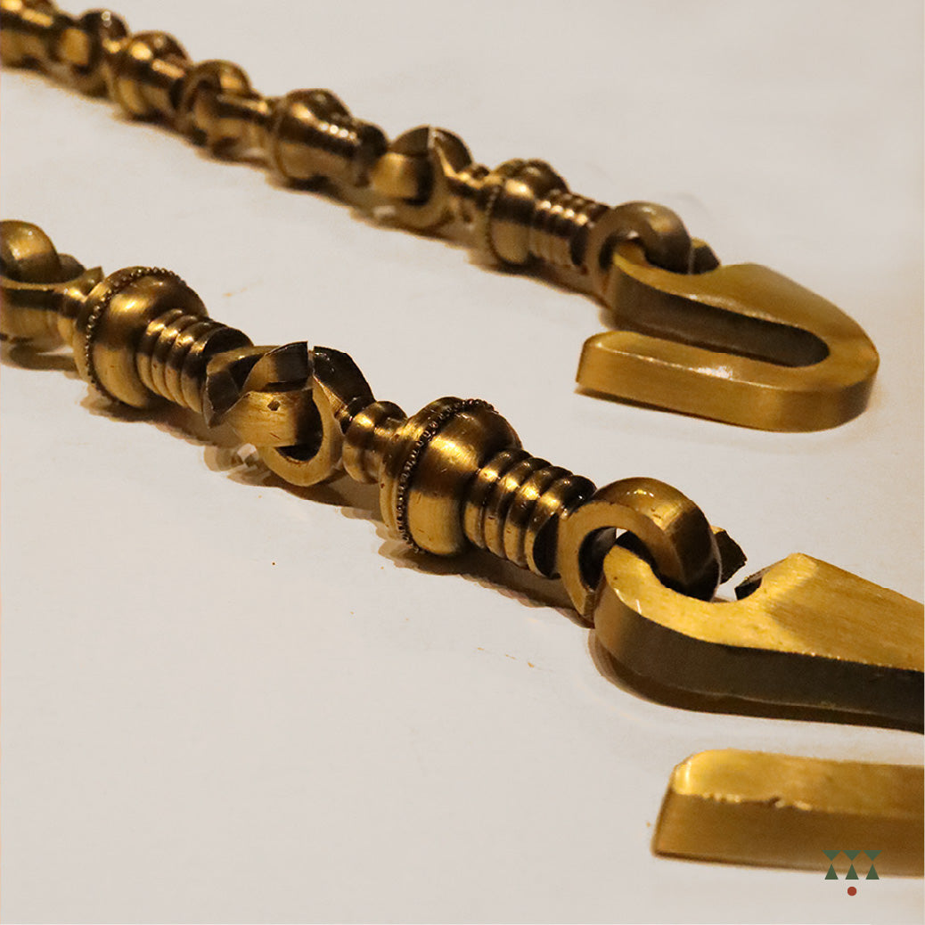 A close up of the pure brass chain links with intricate designs that suspends a swing