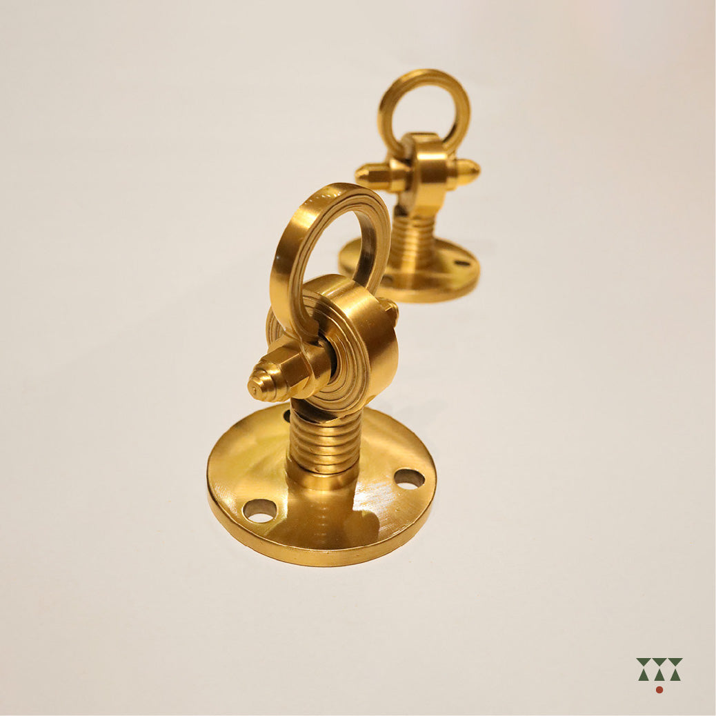 A close up of the pure brass individual ceiling hooks with intricate designs and motifs that suspend a swing