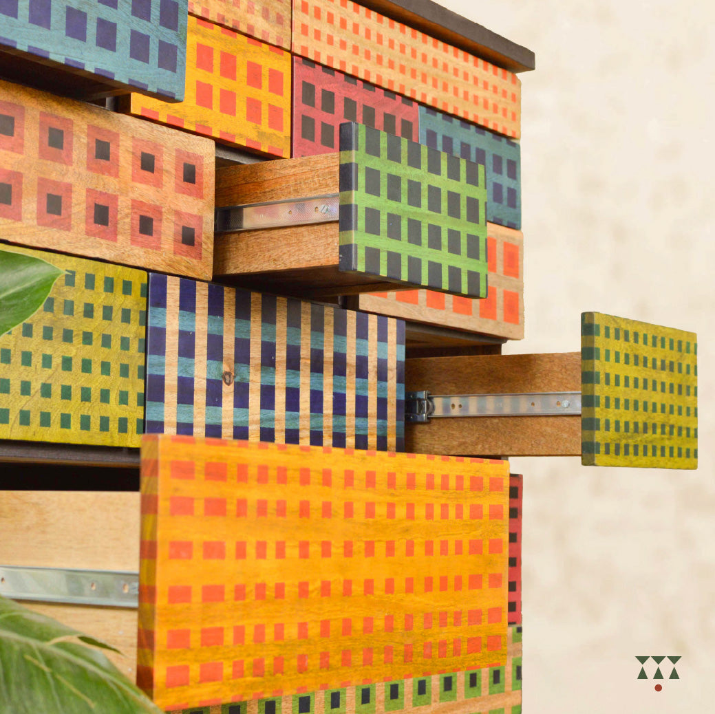 A close up ofwooden chest with patterns inspired from madras checks.