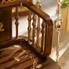 A close up of a wooden swing crafted with Kolam, Annapakshi and floral designs and turning details on the backrest and seat 