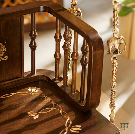 A close up of a wooden swing crafted with Kolam, Annapakshi and floral designs and turning details on the backrest and seat 
