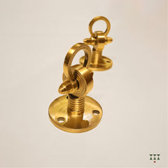 A close up of the pure brass individual ceiling hooks with intricate designs and motifs that suspend a swing
