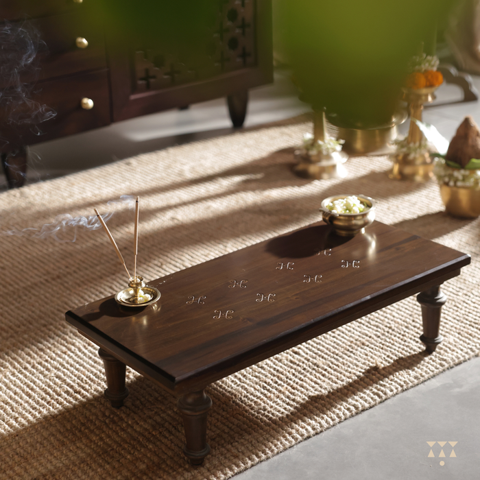 A wooden offering table with incense and brass bowl with of flowers on it
