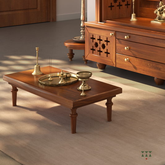 A naivedya table placed in front of wooden temple with brass pooja accessories on it.