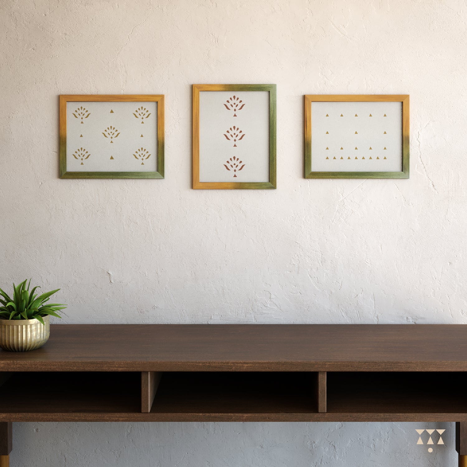 Set of 3 large wooden frames tinted in a gradation of mustard yellow & moringa green placed on a wall above a console table
