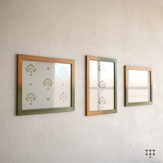 Set of 3 large wooden frames tinted in a gradation of mustard yellow & moringa green placed on a wall above a console table