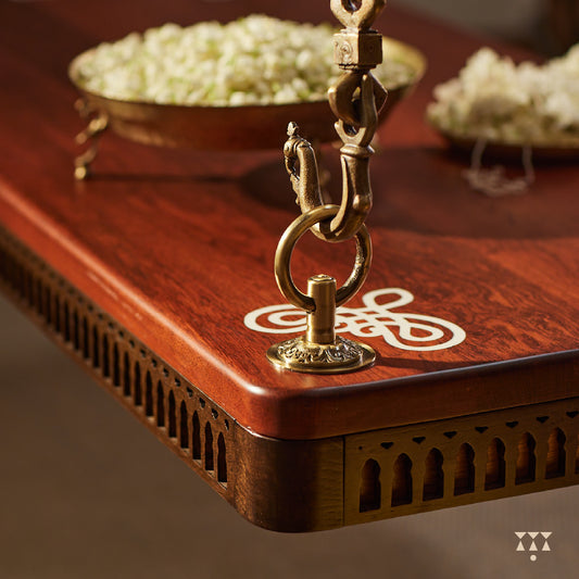 Close up of a solid wood swing with a pure brass animal motif chain and Kolam patterns inlayed in the seat