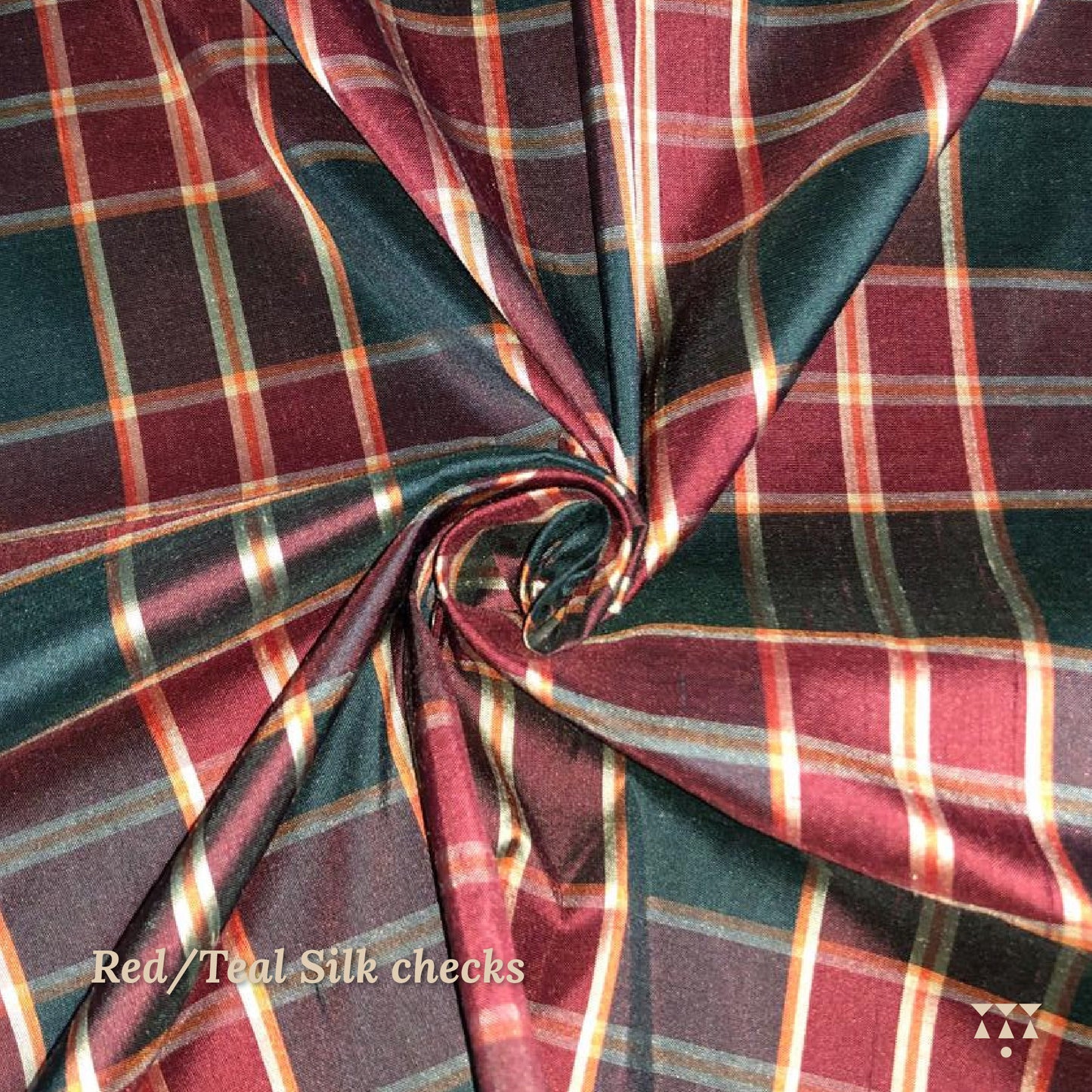 Close up of a red and teal checked silk upholstery option for a solid wood wing chair