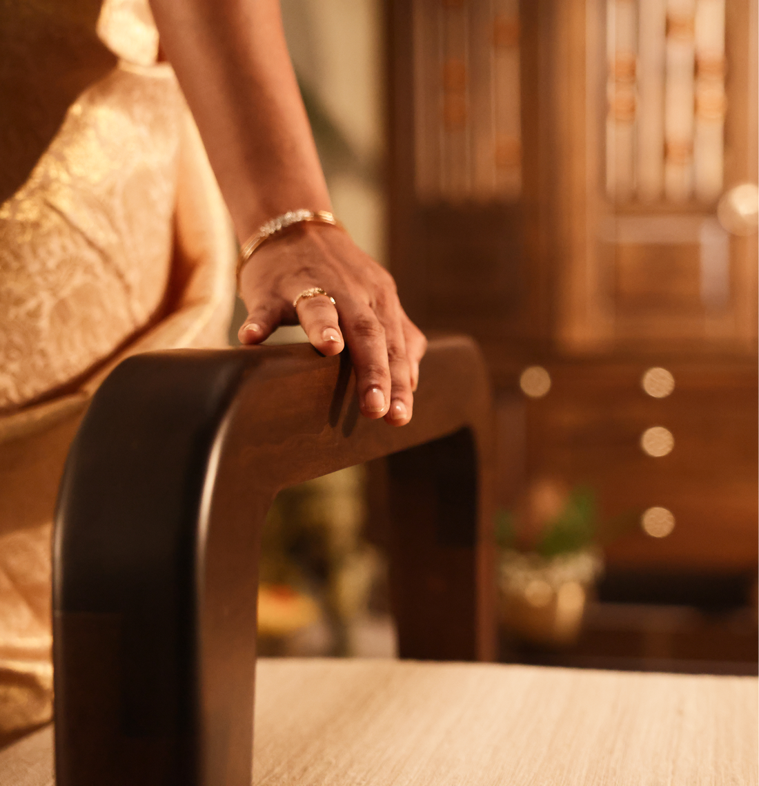 Hand resting on the curved solid wood backrest of a Furnicheer bench with a beige upholstered seat.
